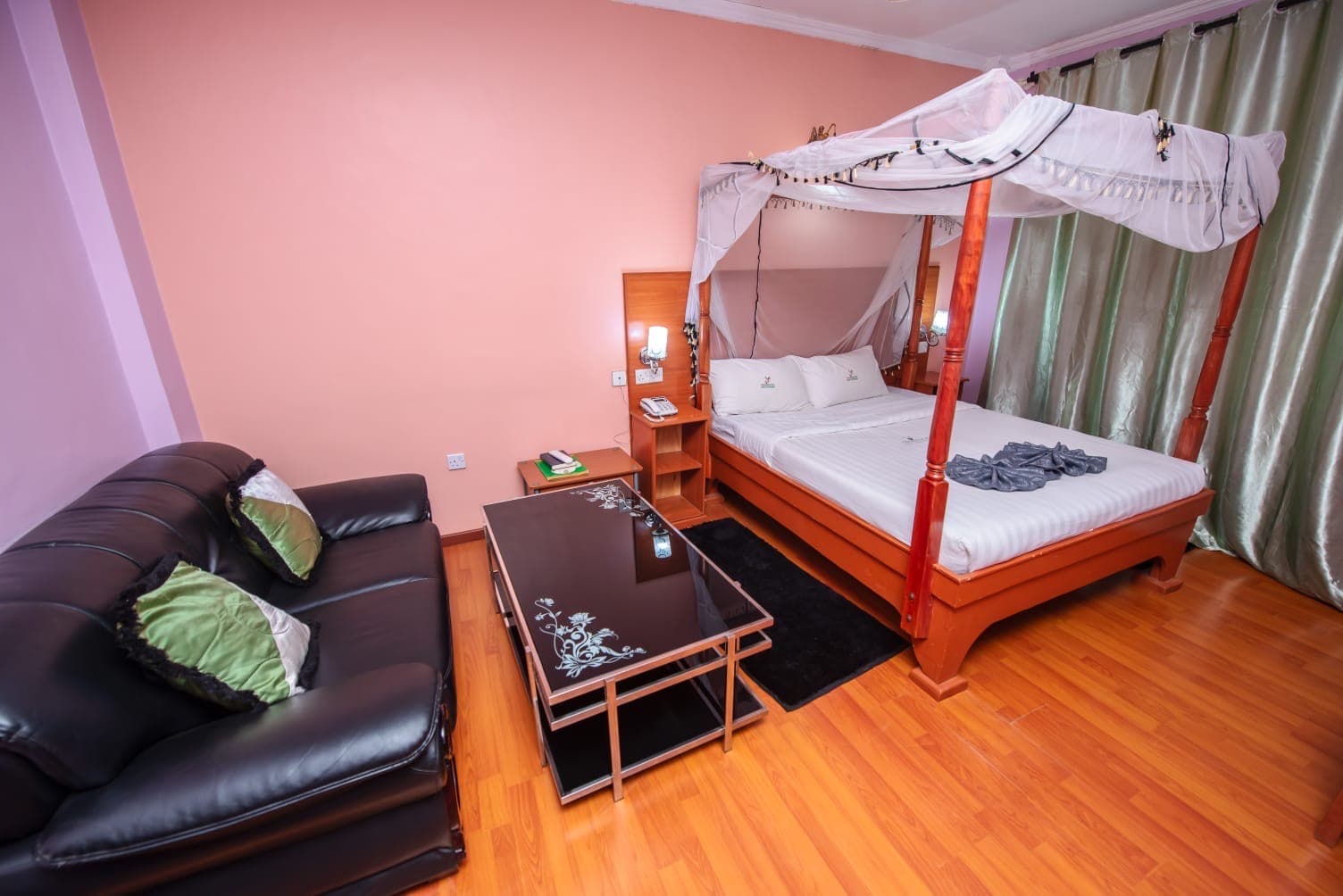 A mosquito-net canopy bed and sofa in a room at The Starbucks Hotel, Eldoret