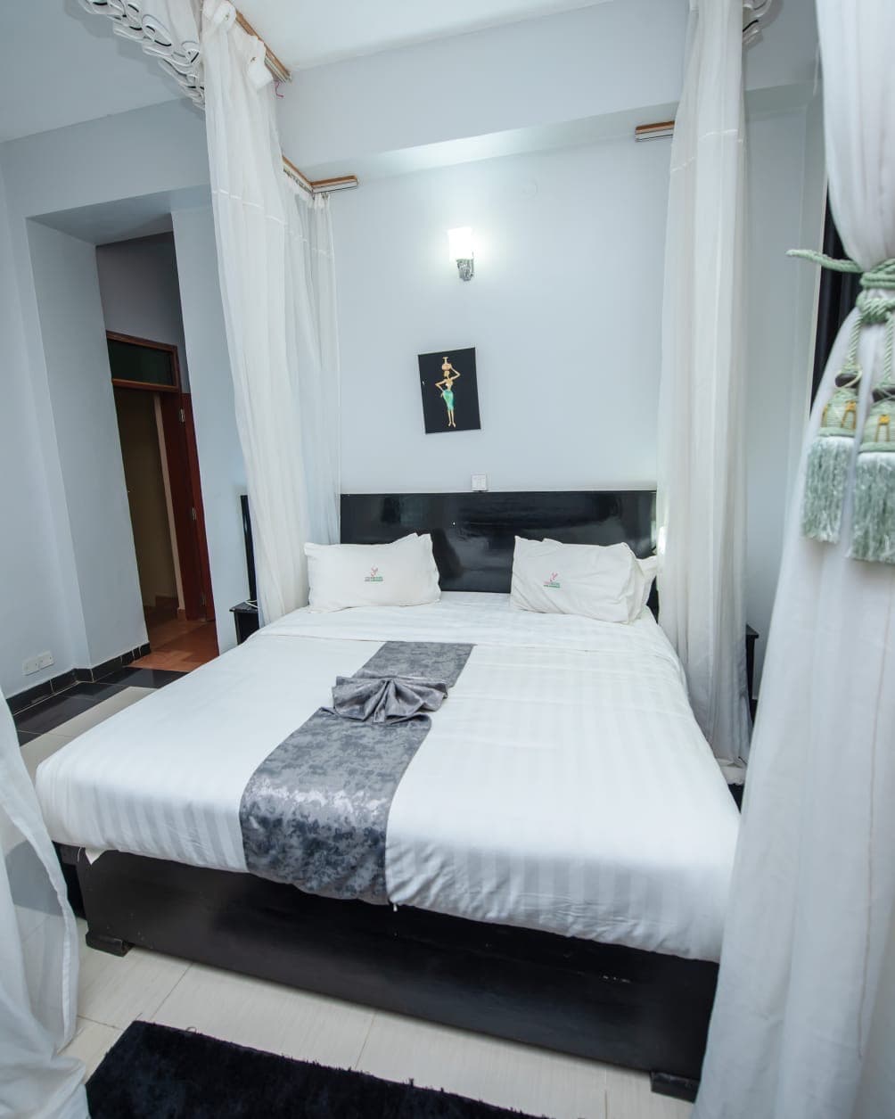 A four-poster bed with tasselled drapes in a room at The Starbucks Hotel, Eldoret